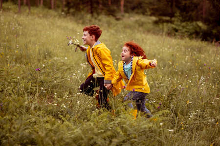 Happy siblings running in grassy meadow
