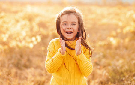Excited girl clapping hands in field