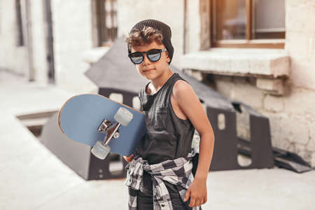 Hipster kid with skateboard on streetの写真素材