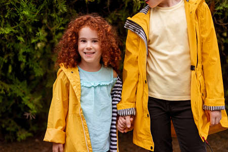 Happy ginger girl with brother standing in forestの写真素材