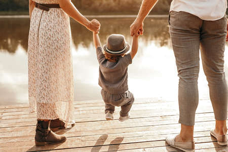 Crop parents swinging child over pier