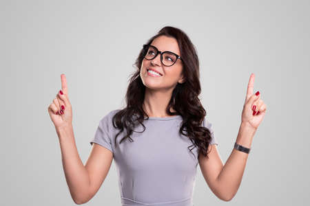 Cheerful woman in glasses pointing upの写真素材