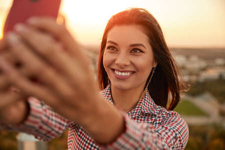 Cheerful woman taking selfie during sunsetの写真素材