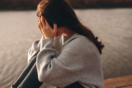 Lonely upset woman sitting near river
