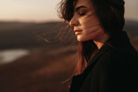 Thoughtful woman standing alone near lake