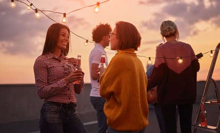 Company of friends relaxing on terrace at sunsetの写真素材