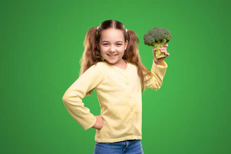 Cheerful girl with fresh broccoli in studioの写真素材