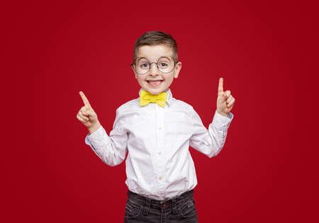 Cheerful stylish little boy pointing up