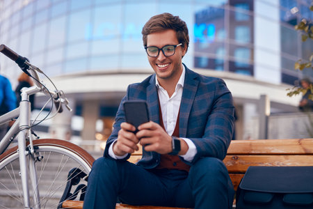 Happy formal guy with bike text messaging on smartphoneの写真素材