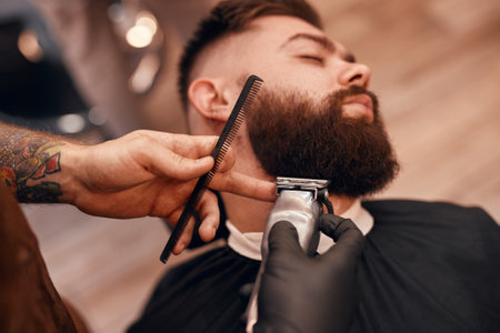 Crop barber trimming beard of dandy clientの写真素材