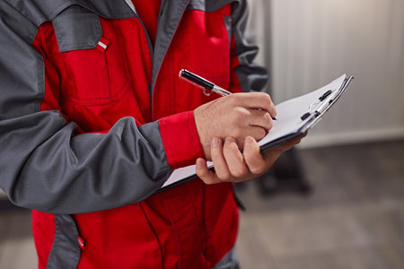Crop mechanic making notes on clipboardの写真素材