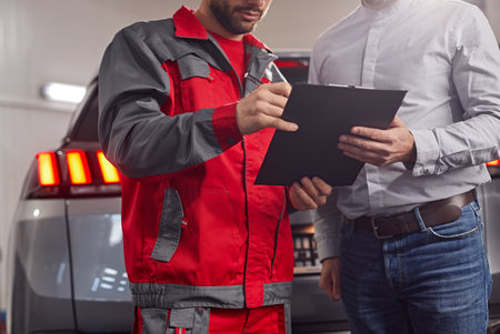Mechanic and customer filling documents in car service workshopの写真素材
