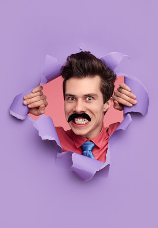 Funny detective tearing hole in paperの写真素材