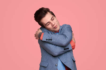 Dreamy young man embracing himselfの写真素材