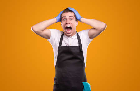 Scared male housekeeper screaming and looking at cameraの写真素材