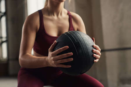 Crop sportswoman squatting in gymの写真素材