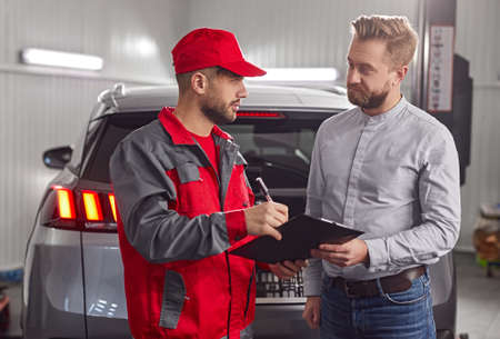 Customer and mechanic with checklist discussing work in auto service centerの写真素材