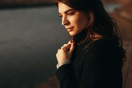 Lonely woman in coat standing near riverの写真素材