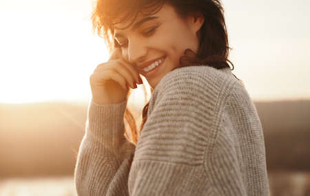 Happy woman smiling in nature at sunset