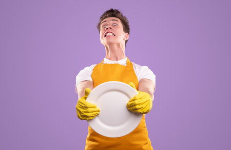 Funny man in apron and gloves washing dishes
