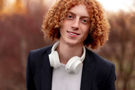 Positive ginger man with headphones looking at camera