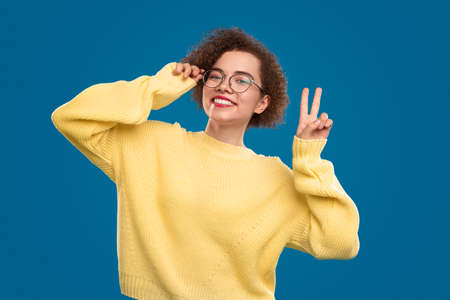 Cheerful woman in glasses showing v signの写真素材