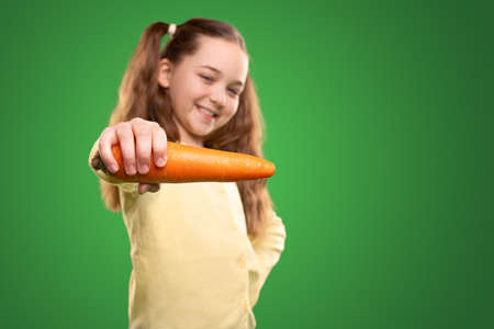 Smiling girl showing fresh carrotの写真素材