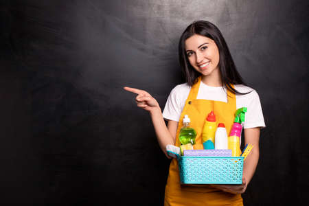 Cheerful housewife with detergents pointing awayの写真素材