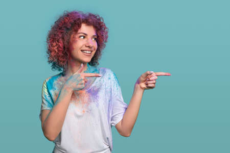 Smiling hipster woman with Holi colors pointing awayの写真素材