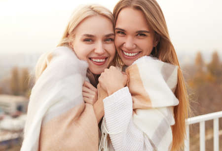 Laughing girlfriends hugging in cold dayの写真素材