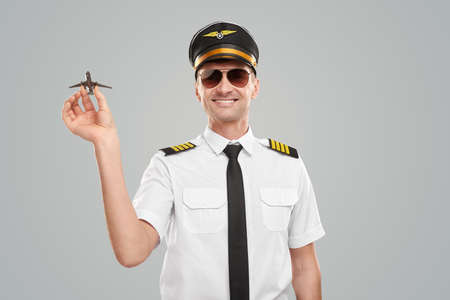 Cheerful pilot in uniform with toy airplaneの写真素材