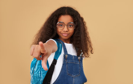 Smiling black schoolgirl pointing at cameraの写真素材