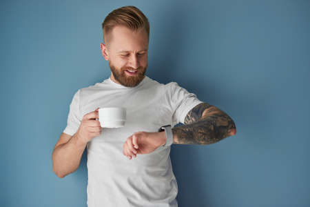 Bearded man with coffee checking timeの写真素材