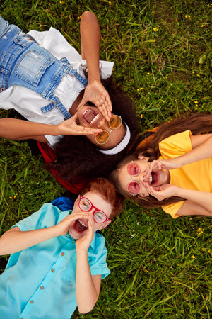 Happy diverse kids lying on grass and screaming