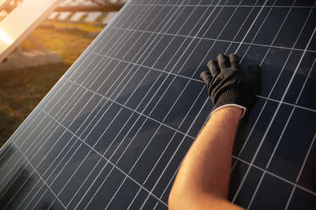 Worker in glove cleaning solar panel