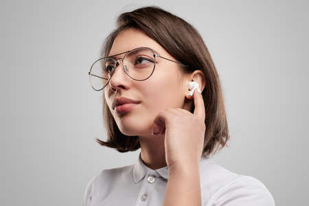 Young businesswoman adjusting TWS earbuds