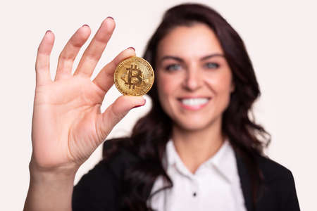 Smiling confident woman showing bitcoin coinの写真素材