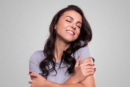 Dreamy woman embracing herself and smiling