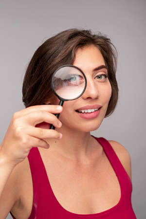 Smiling woman looking through magnifying glass