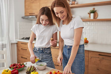 Happy mother and daughter cooking together in kitchenの写真素材
