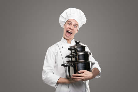 Excited cook with kit of saucepans