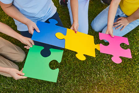 Crop kids solving puzzle on lawnの写真素材
