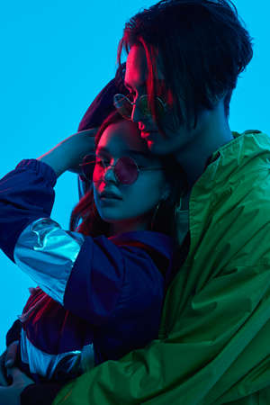 Trendy young couple hugging under neon light