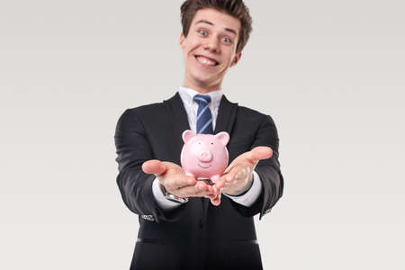 Cheerful businessman showing piggy bankの写真素材