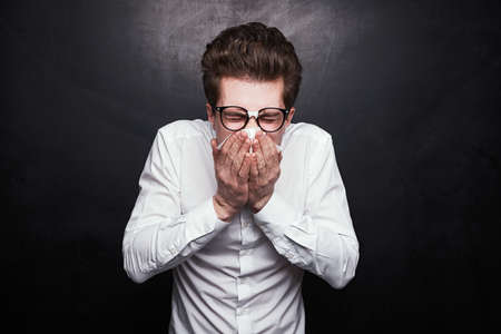 Sick nerdy man sneezing in studio