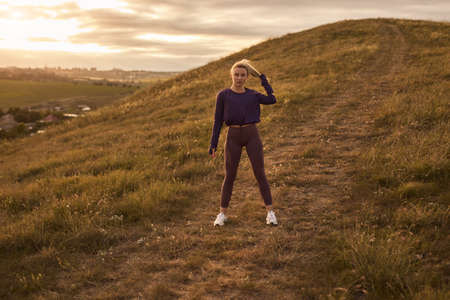 Active woman in sportswear standing on hillの写真素材