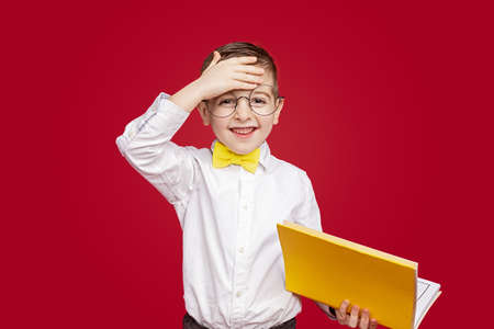 Tired schoolboy wiping forehead during lessonの写真素材