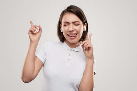 Cheerful woman in earbuds dancing in studio
