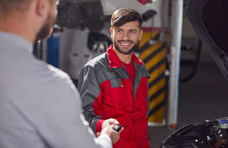 Male mechanic taking keys from clientの写真素材