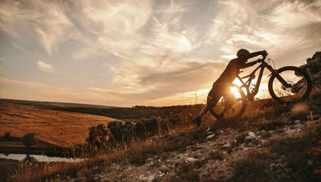 Cyclist with mountain bike at sunsetの写真素材